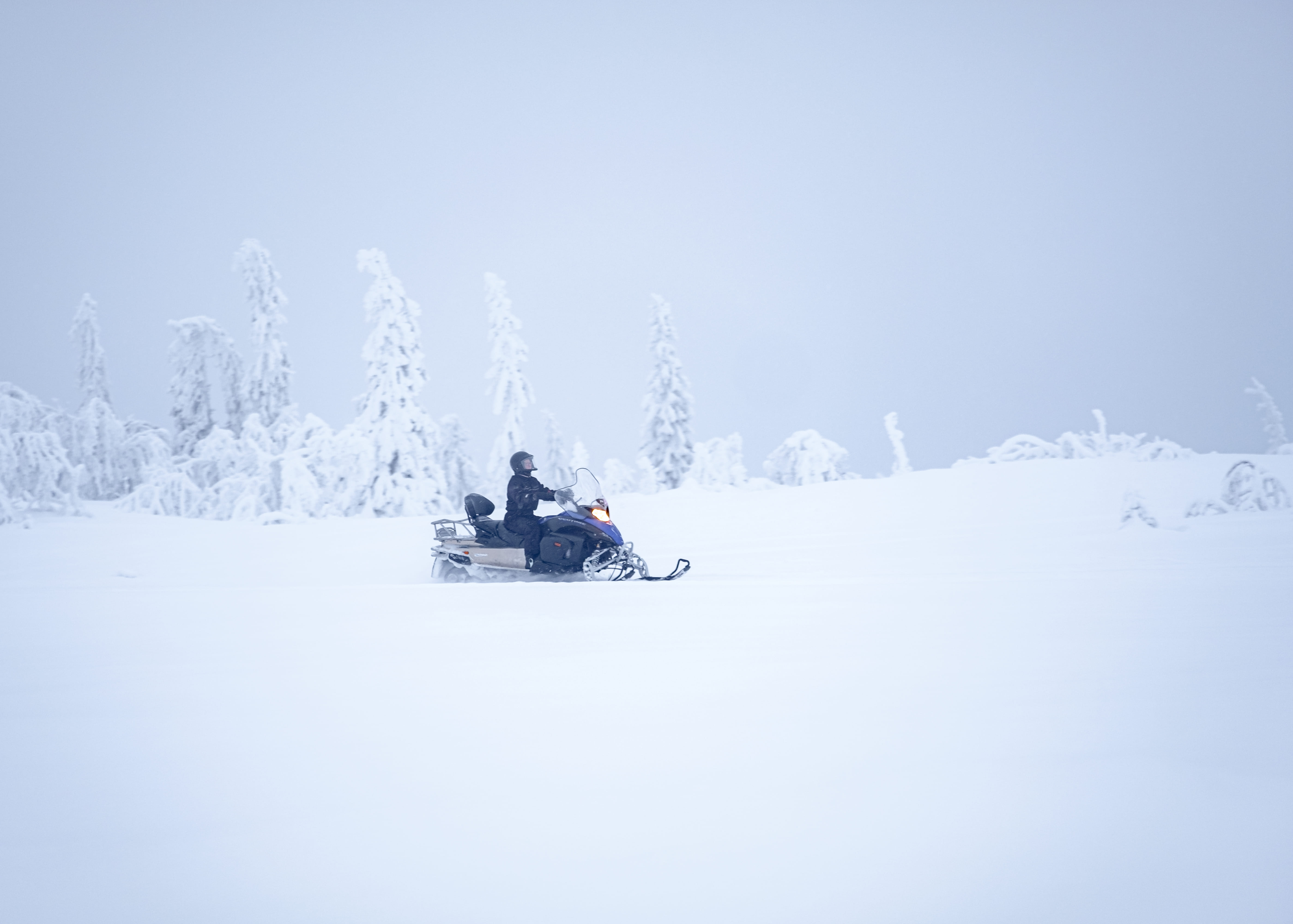 People on snow mobile in snowy mountain against sky