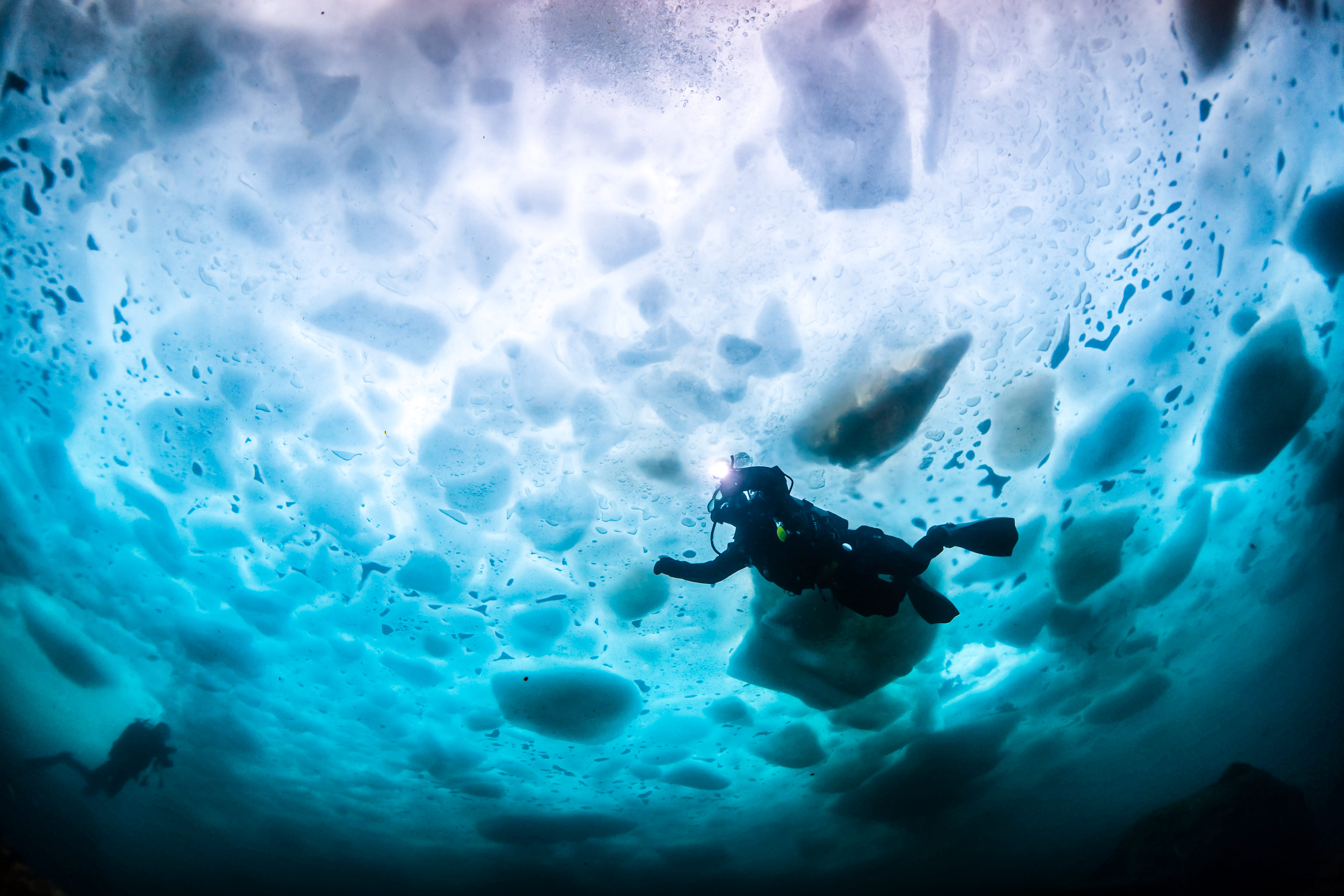 Full length of scuba diver swimming in frozen sea