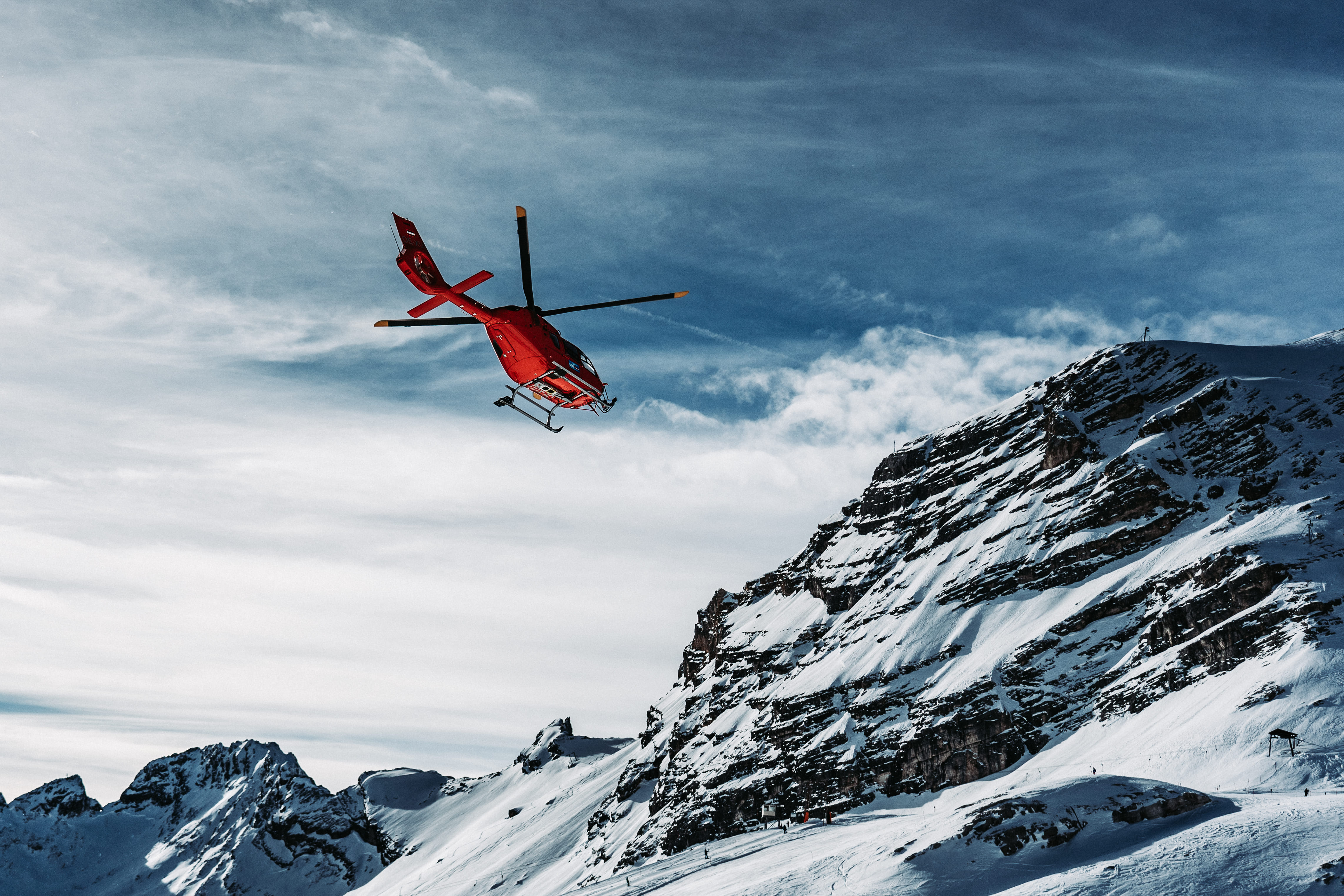 Helicopter flying over snowcapped mountains against sky