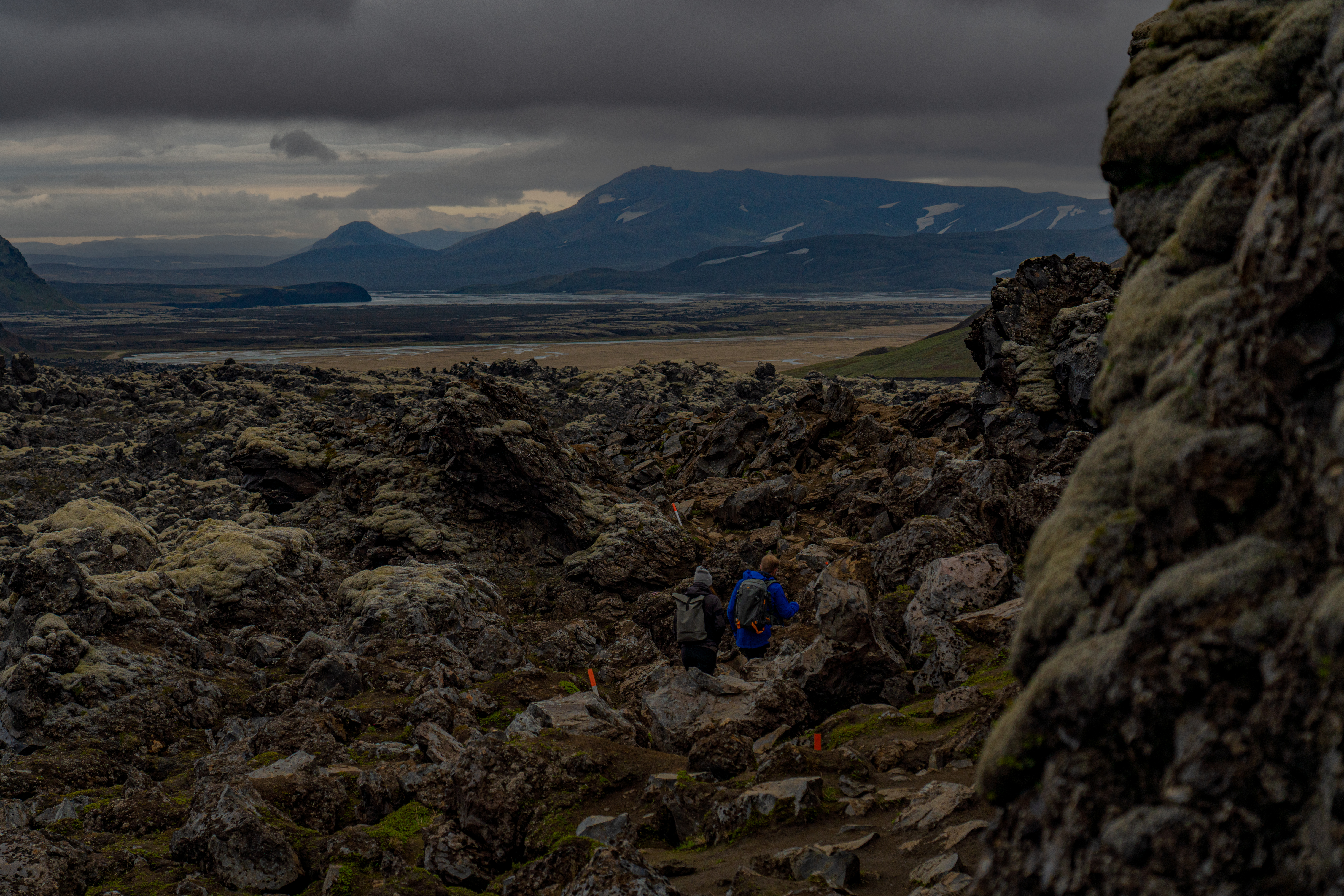 Two people hiking trough a volcanic field of magma in the highlands of iceland